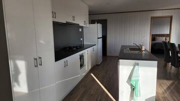 A modern kitchen with white cabinets, a black countertop, and a wooden floor.