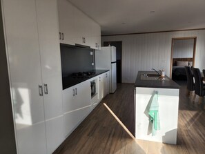 Een moderne keuken met witte kasten, een zwart aanrecht en een houten vloer.