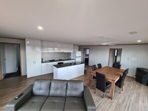 A modern kitchen with white cabinets, a central island, and a dining area with a wooden table and chairs.