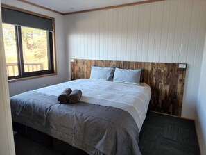 A bedroom with a bed, a window, and a wooden headboard.