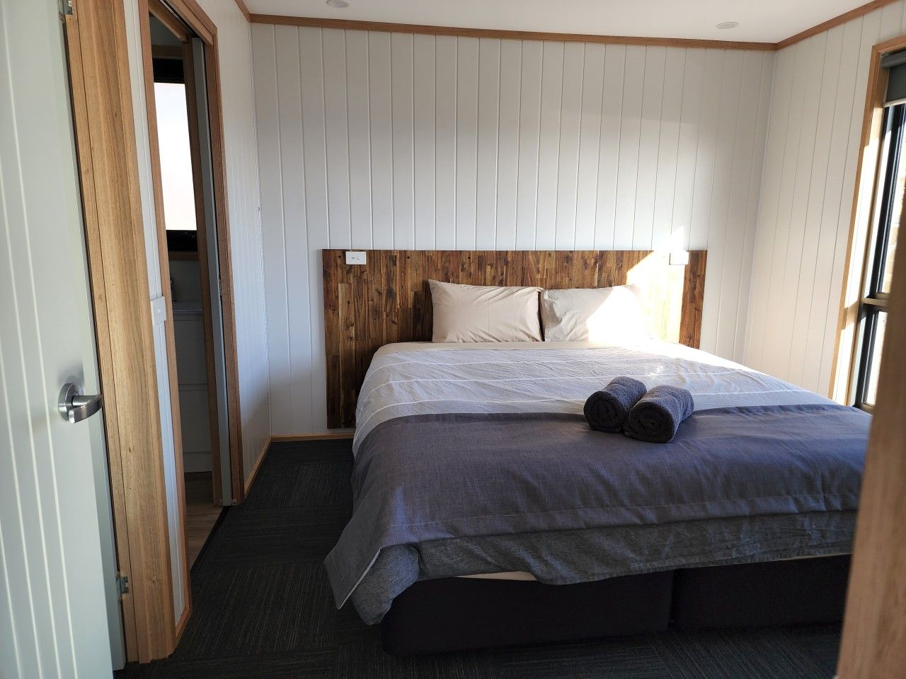 A bedroom with a bed, a wooden headboard, and a door leading to another room.