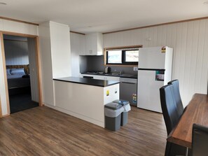 Cocina compacta con una isla central, una mesa de comedor y un refrigerador.