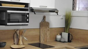 Une cuisine moderne avec des meubles blancs, un four à micro-ondes, un grille-pain et une planche à découper en bois.