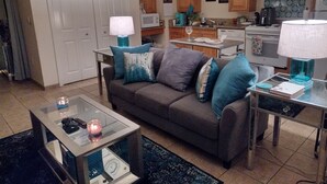 Uma sala de estar com sofá, mesa de centro e cozinha ao fundo.