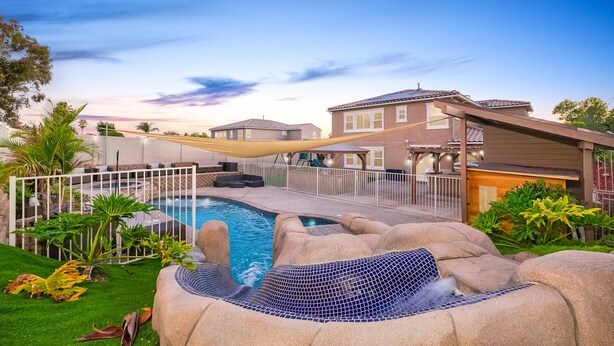 Ein Garten mit Pool, Whirlpool und überdachter Terrasse.