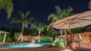 A nighttime outdoor pool area with a hot tub, a wooden deck, and a large umbrella. - Luxurious spa-like oasis with pool, 4bdr/ 3br (Elk Grove)