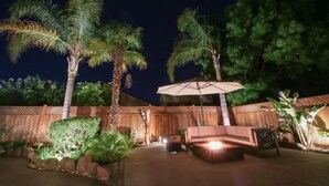 An outdoor patio area with a seating arrangement, a fire pit, and a large umbrella. - Luxurious spa-like oasis with pool, 4bdr/ 3br (Elk Grove)
