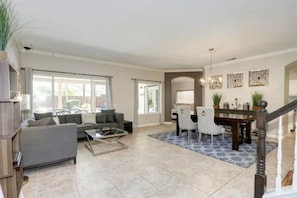 A spacious living room with a sofa, coffee table, and dining area with chairs and a table. - Luxurious spa-like oasis with pool, 4bdr/ 3br (Elk Grove)