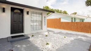 Une maison avec une porte noire, une fenêtre à carreaux et le numéro « 8552 » peint sur le mur.