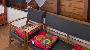 Interno di una baita di legno con una finestra, tende e una panca con cuscini colorati.
