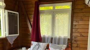 Camera da letto in una baita di legno, con un letto, due comodini, una lampada e una finestra con tende.