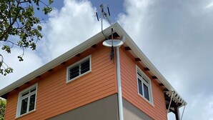 Una casa a due piani con facciata arancione, un'antenna parabolica e un portone del garage in vista.