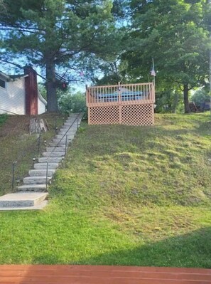 Enjoy the serene outdoor space with a wooden deck, steps, and a lush lawn.