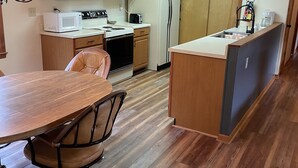 A compact kitchen with wooden cabinets, a microwave, stove, and a refrigerator. - Amazing Long Range Views in central Maggie Valley. (Maggie Valley)