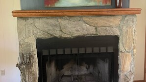 A stone fireplace with a painting above it and a vase on the mantel. - Amazing Long Range Views in central Maggie Valley. (Maggie Valley)