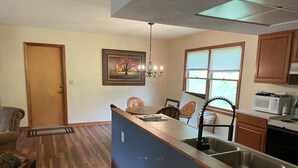 A kitchen with a central island, wooden cabinets, a microwave, and a sink. - Amazing Long Range Views in central Maggie Valley. (Maggie Valley)