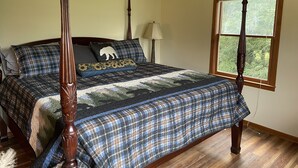 A bedroom with a four-poster bed, a window with a view of greenery, and a lamp on a bedside table. - Amazing Long Range Views in central Maggie Valley. (Maggie Valley)