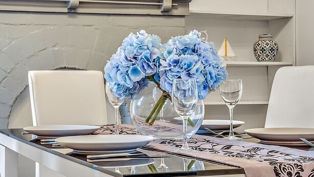 A dining table set with plates, cutlery, and a vase of blue flowers. - The Cottage - Lithgow (Lithgow)