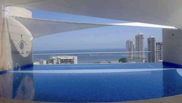 Une piscine offrant une vue sur le paysage urbain et l’océan.