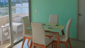 Un coin repas avec une table et des chaises, un ventilateur de plafond et une vue à travers une porte vitrée.