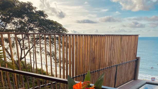 A table set for two with a view of the ocean, a wooden fence, and tropical plants. - Beach Eco Stays Hotel Boutique Lagoinha (Paraipaba)