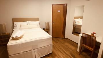 Un dormitorio ordenado con cama, mesitas de noche, un escritorio y una silla.