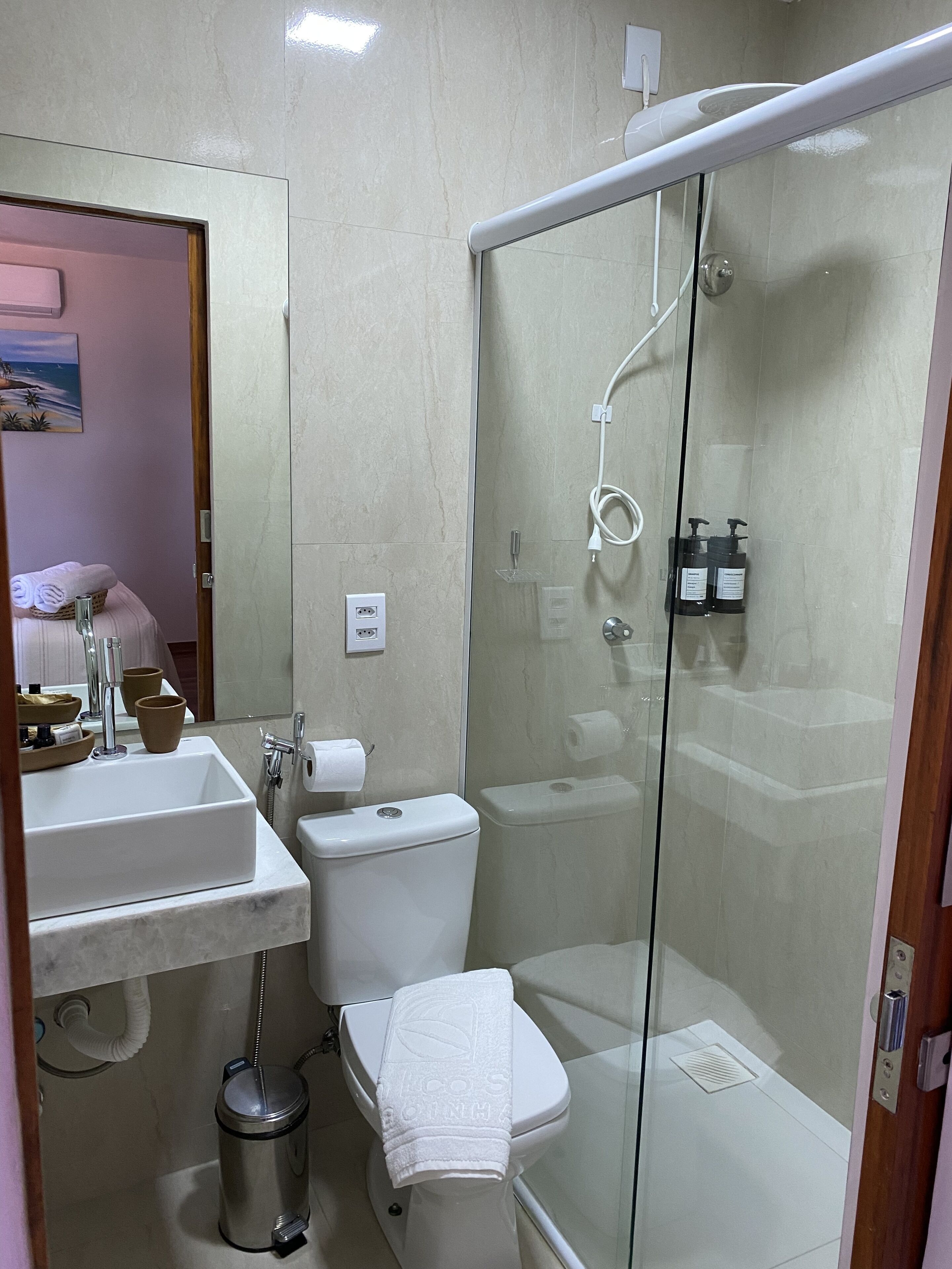 A modern bathroom with a glass-enclosed shower, a sink, and a toilet.