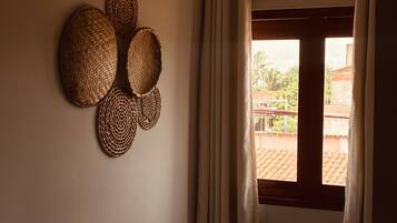 A room with a window, curtains, and woven wall decorations.