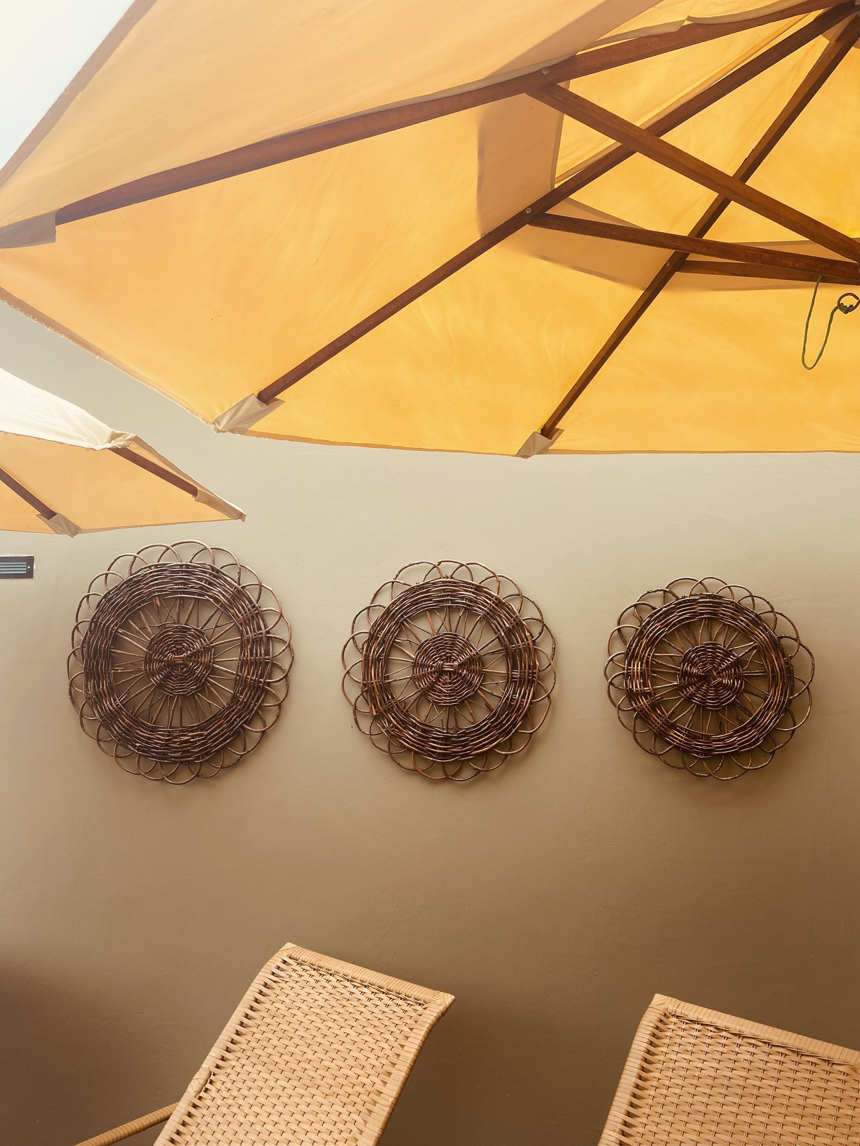Un plafond orné d’un parasol jaune et de trois anneaux métalliques décoratifs fixés au mur.