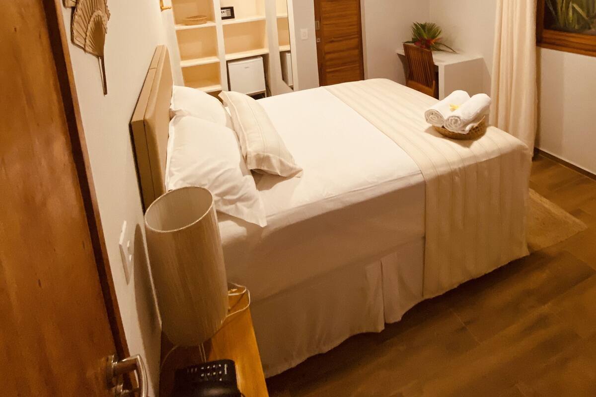 A bedroom with a bed, bedside table, lamp, and a TV mounted on the wall.