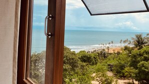 A window with a view of the ocean and beach, a wooden door, and a curved glass structure. - Beach Eco Stays Hotel Boutique Lagoinha (Paraipaba)