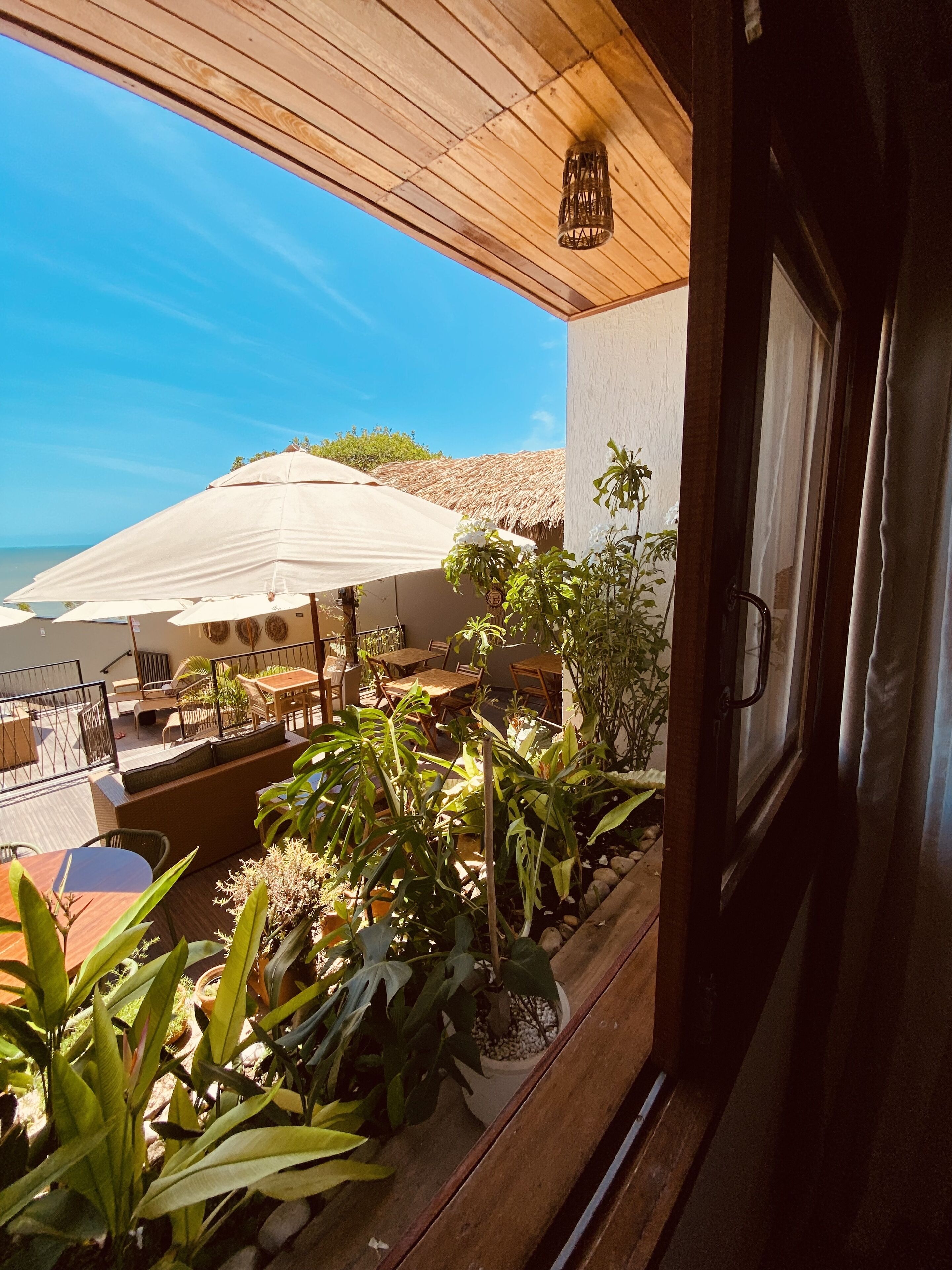 Ein Balkon mit Sitzgelegenheit im Freien, Blumentöpfen und Blick auf den Ozean.