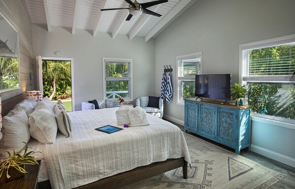 A bedroom with a bed, a television, a blue cabinet, and a window with blinds.