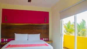 A bedroom with a large bed, a wooden headboard, and a balcony with yellow walls. - Hotel Happy Beach (Zihuatanejo)