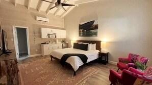 Un dormitorio con cama, escritorio, silla y un cuadro en la pared.