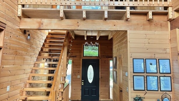 A wooden cabin with a central staircase, a balcony, and a door with framed pictures. - 3 level cabin on Mt Mitchell golf course (Burnsville)
