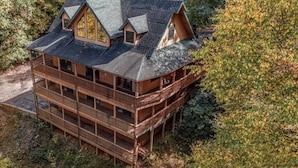 A multi-story log cabin with a balcony on each floor, surrounded by dense forest. - 3 level cabin on Mt Mitchell golf course (Burnsville)
