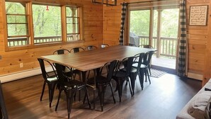 A wooden cabin with a large dining table surrounded by chairs, a sign reading "The Gathering Place," and large windows with curtains. - 3 level cabin on Mt Mitchell golf course (Burnsville)