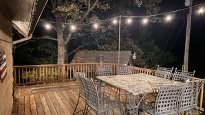 Une terrasse extérieure avec une table et des chaises, des guirlandes lumineuses et un arbre.