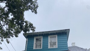 Una casa a due piani con un portico, una scala che conduce all'ingresso e una porta ben visibile.