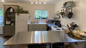 Una cucina moderna con piani di lavoro in acciaio inossidabile, un'isola centrale con sgabelli da bar e diversi elettrodomestici.