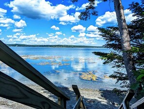 Vista lacustre con muelle de madera, aguas tranquilas y cielo despejado.