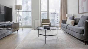 A modern living room with a large TV, a sofa, a coffee table, and a chair. - Trendy South Bank 1BR w/ Pool, Gym & Concierge, nr Tube, by Blueground (London)