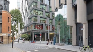 A modern building with a glass facade, a bicycle parked outside, and a pedestrian crossing. - Trendy South Bank 1BR w/ Pool, Gym & Concierge, nr Tube, by Blueground (London)