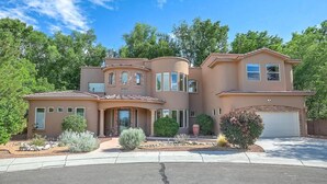 A two-story house with a curved facade, multiple windows, and a garage. - A Big House (Albuquerque)