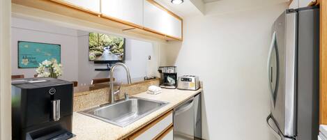 A compact kitchen with a stainless steel sink, a coffee maker, and a dishwasher.