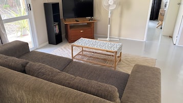 Una sala de estar con un sofá, un televisor, un ventilador y una mesita.
