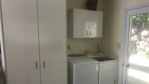 A laundry room with a washing machine, a dryer, and a cabinet with two doors.