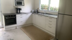 A kitchen with white cabinets, a microwave, a stove, a sink, and a refrigerator.