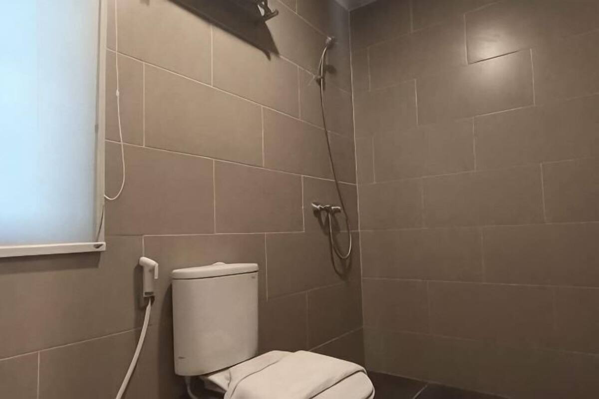 A bathroom with a toilet, shower, and tiled walls.